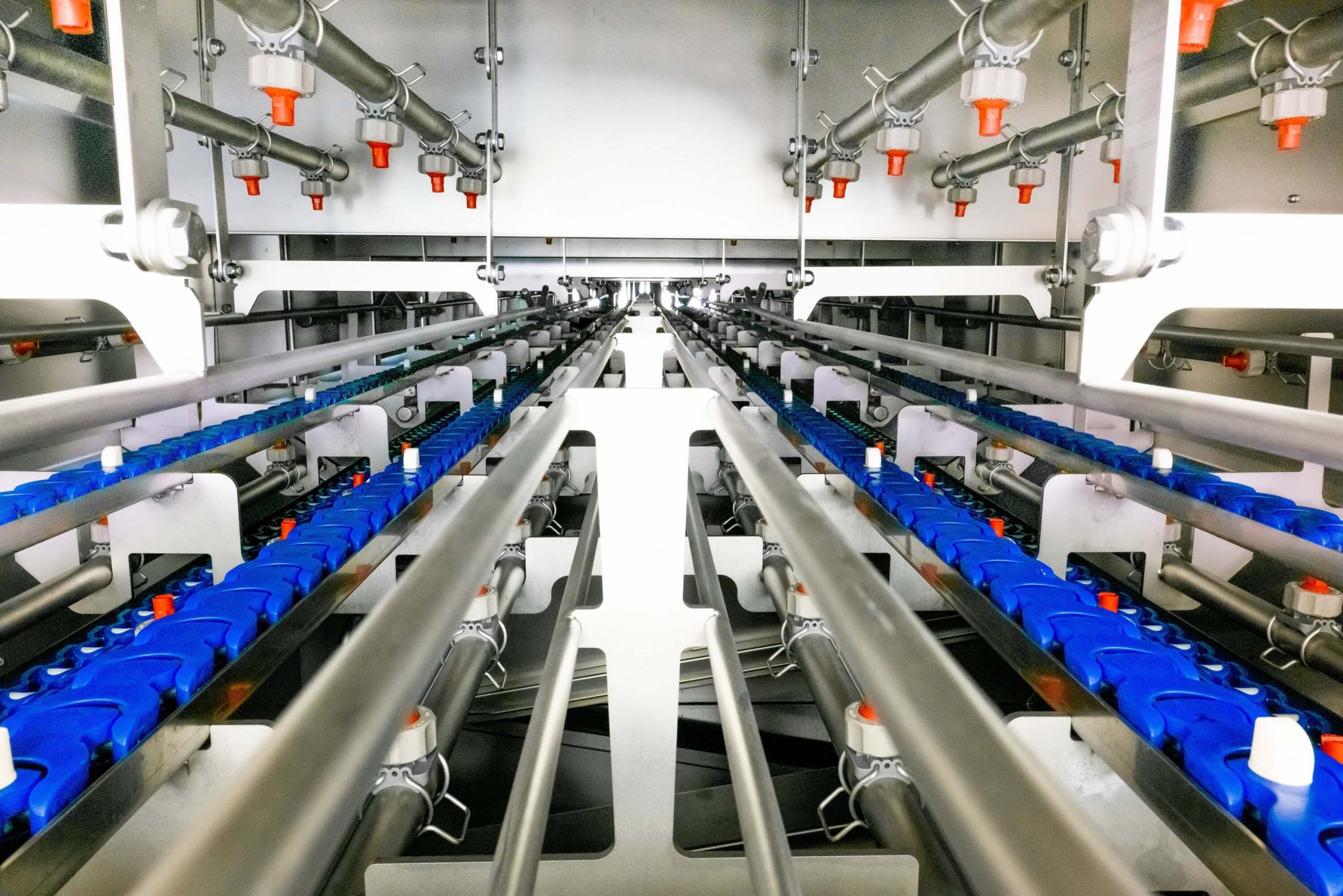 Innenansicht des Clip-Eyelet Düsensystems und der Transportbänder einer zweispurigen industriellen Durchlaufwaschanlage