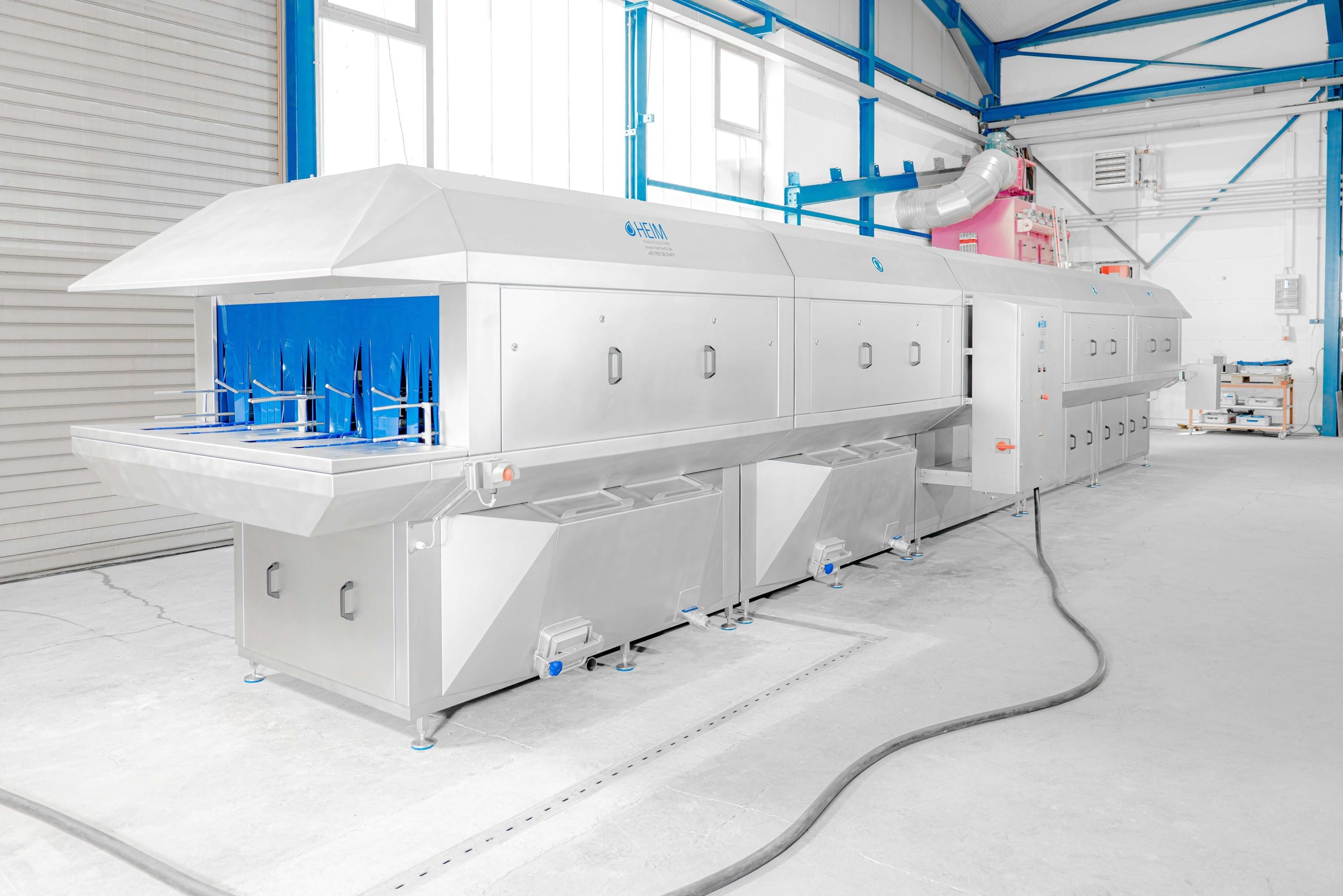 Große zweispurige Kistenwaschanlage von Heim-EDT aus Edelstahl in einer Industriehalle für hohen Kistendurchsatz.
